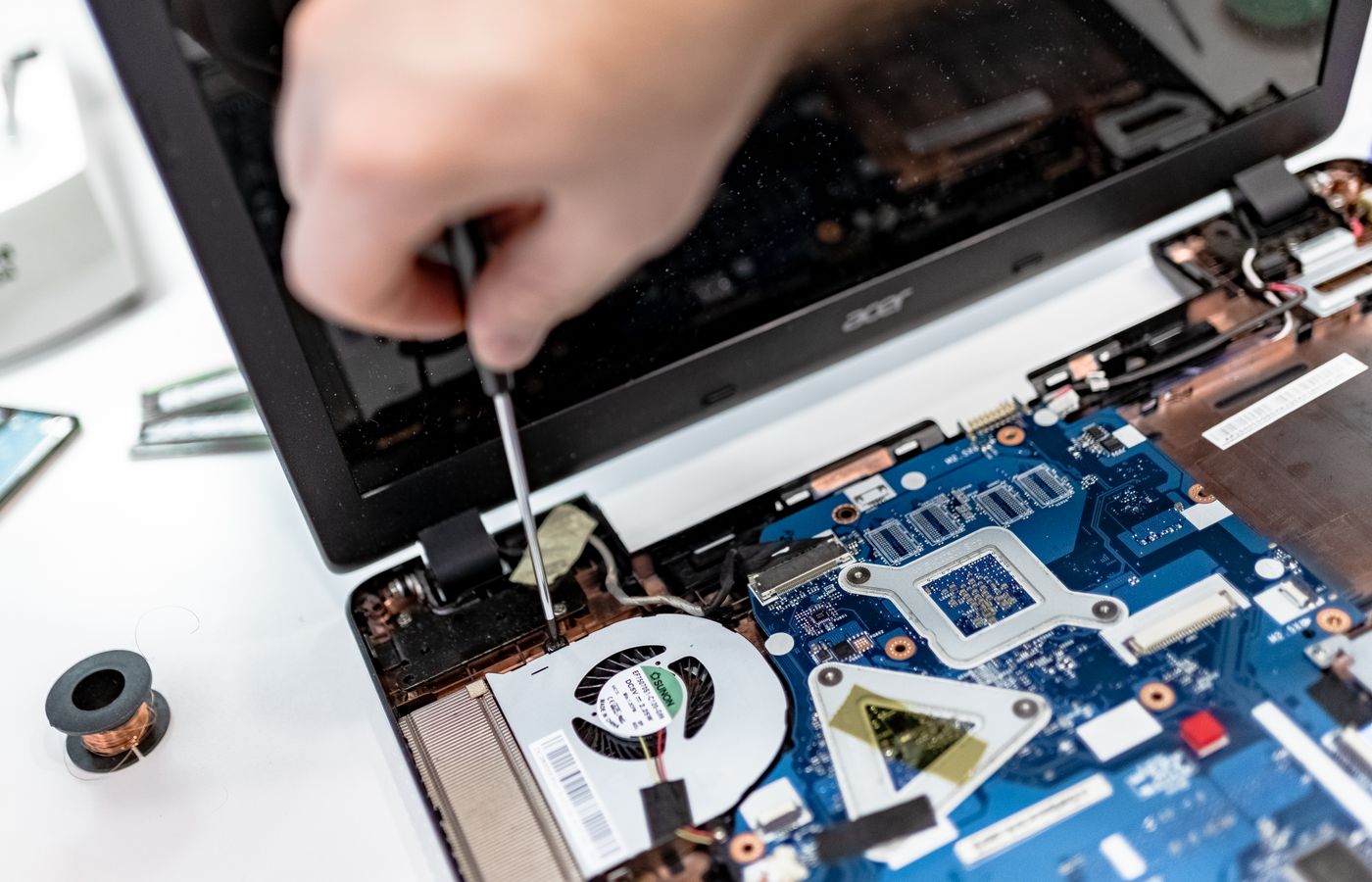 Hands repairing components inside an open laptop